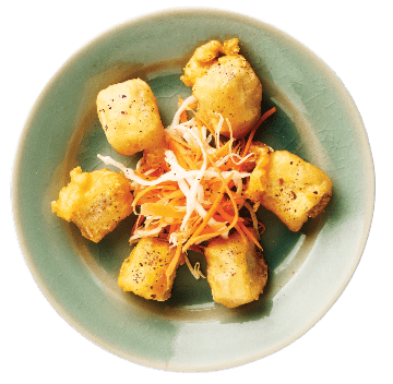 Five golden fried tofu cubes arranged in a circle on a green plate, with shredded carrot and cabbage garnish in the center.